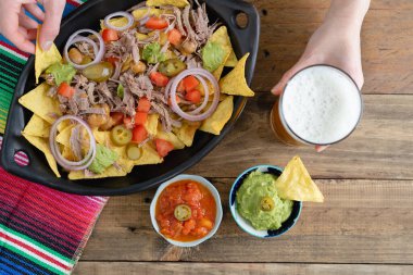 Bir tepsi nachos et ve bir bardak biraya tutunarak. Salsa soslu kâseler. Üst Manzara. Boşluğu kopyala.