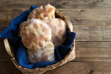 Eski ahşap tahtaların üzerinde ev yapımı pide ekmeği olan sepet. Uzayı kopyala en üstteki görünüm.