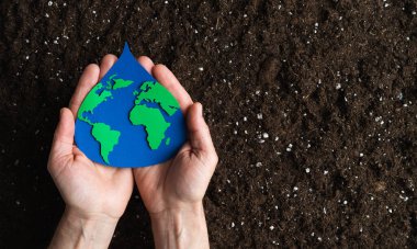 Elleri su damlacıklı kağıt kesikli dünya haritası doğal bir yeryüzü zemininde. Uzayı kopyala Üst görünüm.