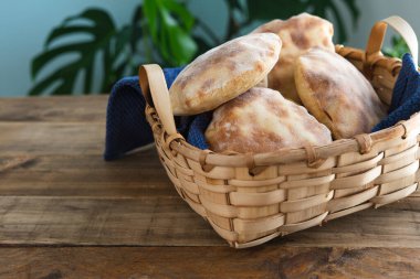 Tahta masanın üzerinde ev yapımı pita ekmeği olan ahşap bir sepet. Boşluğu kopyala.