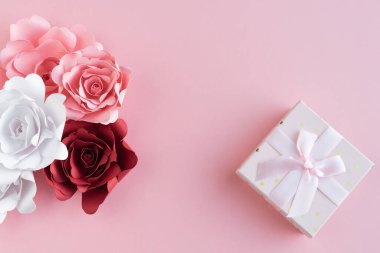 Pembe arka planda fiyonk ve kağıt gül süsü olan hediye kutusu. Uzayı kopyala Anneler Günü. Sevgililer Günü.