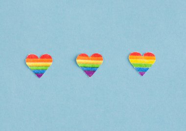 Mavi arka planda LGBTQ gökkuşağı bayrağı renginde üç kupa. Boşluğu kopyala.