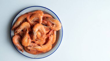 Beyaz arka planda pişmiş karides dolu beyaz tabak. Uzayı kopyala Üst görünüm.