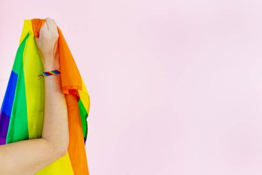 Kadının kolu LGBTQ + bayrağı ve elinde gökkuşağı rengi olan bilezik gösteriyor. Boşluğu kopyala.