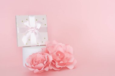 Hediye kutusu ve kağıt gül süsüsüyle beyaz dairesel kaide. Boşluğu kopyala.