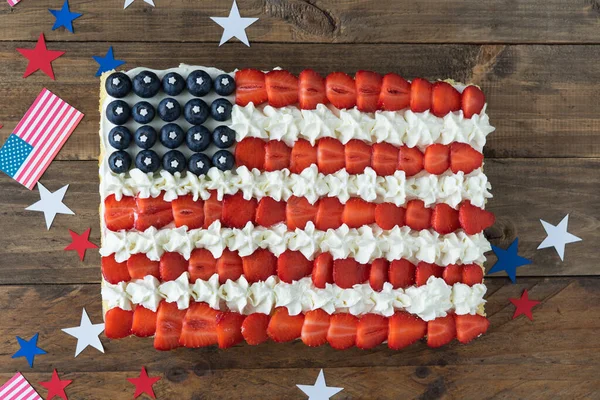 Tahta zemin üzerinde Amerikan bayrağı renginde bayraklar ve yıldız süslemeleri olan pasta. Uzayı kopyala Bağımsızlık Günü Kutlaması. Üst görünüm.