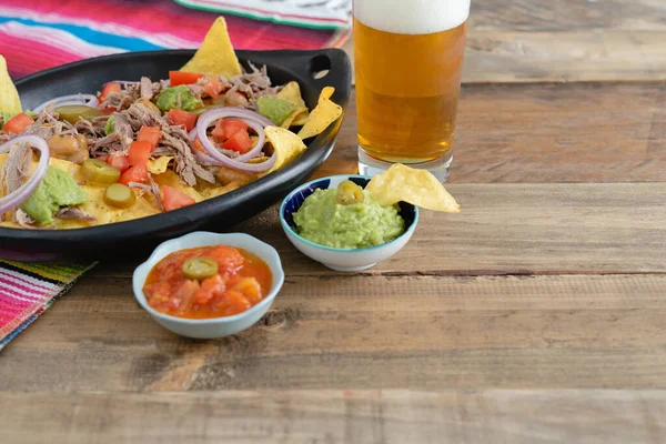 Meksika yemeği. Guacamole ve salsa soslu nachos. Uzayı kopyala Ahşap arka planda bir bardak bira.. 
