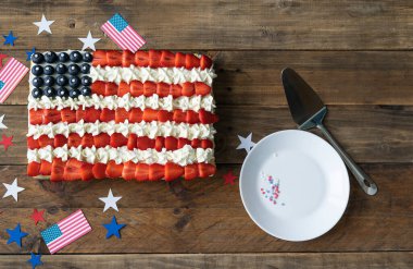 Tahta zemin üzerinde Amerikan bayrağı renginde bayraklar ve yıldız süslemeleri olan pasta. Uzayı kopyala Bağımsızlık Günü Kutlaması. Üst görünüm.