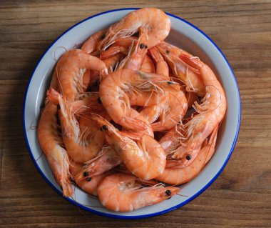 Ahşap arka planda pişmiş karides dolu beyaz tabak. Boşluğu kopyala.