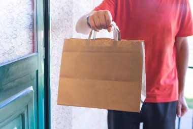 Man delivering a paper bag to the front door. Online shopping. Home delivery.