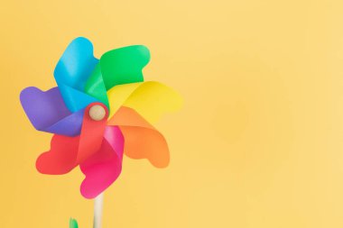 Coloured pinwheel on yellow background. Copy space. Vertical photo. Thematic lgtbq.