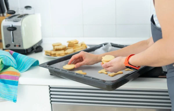 Woman removing cookies from the baking sheet. Home cooking. Copy space. Homemade.
