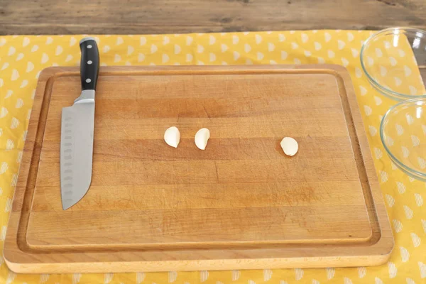 Cooking board with knife and three cloves of garlic ready for cooking. Copy space.