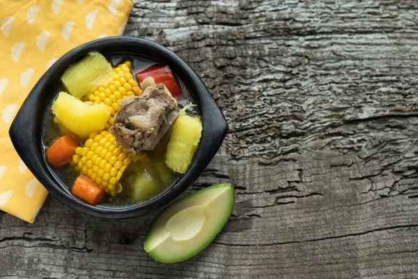 Sancocho, tipik bir Kolombiya yemeği siyah seramik kasede, ahşap arka planda. Uzayı kopyala Üst görünüm.