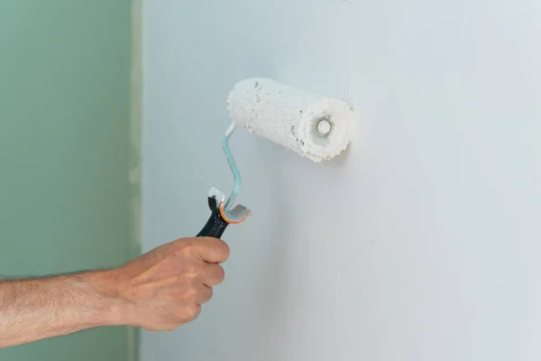 Duvarı bir silindirle elle boyarken yakın plan. Uzayı kopyala Yatay çekim.