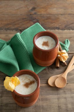 Tahta arka planda kaşık ve bez peçeteyle süslenmiş seramik puding ve tarçın kaseleri. Boşluğu kopyala.