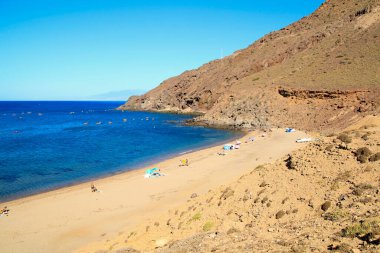 Cabo de Gata, Almeria, İspanya - 3 Eylül 2021: Güneşli bir yaz gününde Corralete sahilinde güneşlenen ve eğlenen insanlar