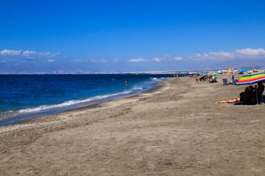 Salinas, Cabo de Gata, Almeria, İspanya - 4 Eylül 2021: İnsanlar Cabo de Gata, Almeria, İspanya 'daki Salinas plajında sabahın keyfini çıkarıyorlar