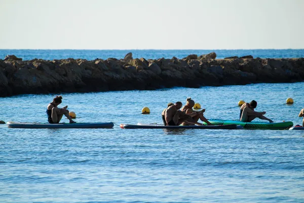 Santa Pola, Alicante, İspanya - 16 Ekim 2021 İspanya 'nın güneşli bir gününde sörf tahtasında yoga yapan bir grup insan