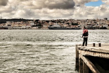 Lizbon, Portekiz- 6 Haziran 2018: Lizbon Şehri Panoramisi ve Almada 'dan Tagus Nehri. Tagus nehrinin kıyısında balık tutan adam.