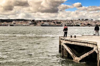 Lizbon, Portekiz- 6 Haziran 2018: Lizbon Şehri Panoramisi ve Almada 'dan Tagus Nehri. Tagus nehrinin kıyısında balık tutan adam.