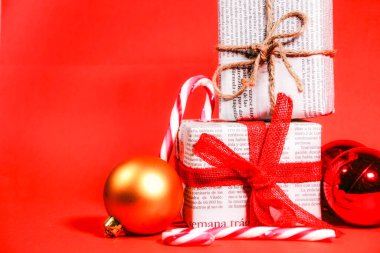 Kırmızı arka planda kırmızı fiyonk ve iple eski gazetelere sarılı hediyeler