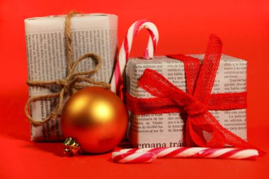 Madrid, İspanya - 12 Kasım 2021: Kırmızı arka planda kırmızı yay ve iple eski gazetelere sarılı hediyeler