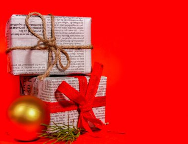 Madrid, İspanya - 12 Kasım 2021: Kırmızı arka planda kırmızı yay ve iple eski gazetelere sarılı hediyeler