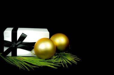 Siyah arka planda Noel süslemesinin yanında beyaz kağıt ve siyah fiyonklarla sarılı hediyeler