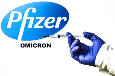 Madrid, İspanya - 29 Kasım 2021: Covid-19 aşı ve Pfizer logosu ile el ele tutuşma şırıngası ve beyaz arka planda yazılmış Yeni Varyant Omicron kelimesi.