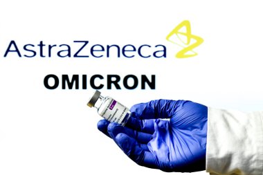 Madrid, İspanya... 29 Kasım 2021 Astrazeneca covid aşısıyla el ele tutuşma şişesi. Arka planda Astrazeneca logosu ve Omicron covid değişken kelimesi yazılı