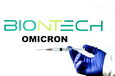 Madrid, İspanya - 29 Kasım 2021 Covid-19 aşısı, Biontech logosu ve beyaz arka planda yazılmış New Variant Omicron kelimesiyle el ele tutuşma şırıngası.