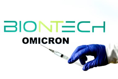 Madrid, İspanya - 29 Kasım 2021 Covid-19 aşısı, Biontech logosu ve beyaz arka planda yazılmış New Variant Omicron kelimesiyle el ele tutuşma şırıngası.
