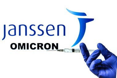 Madrid, İspanya - 29 Kasım 2021: Covid-19 aşılı şırınga ve Janssen logosu ve beyaz arka planda yazılmış Yeni Varyant Omicron kelimesi.