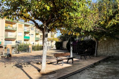 İspanya 'nın Alicante kentindeki tarihi Polop kasabasında bankları ve ağaçları olan küçük bir bahçe.