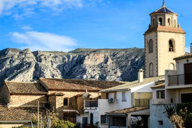 Benimantell köyü ve San Vicente Martir Kilisesi manzarası. Arkaplanda dağlar.