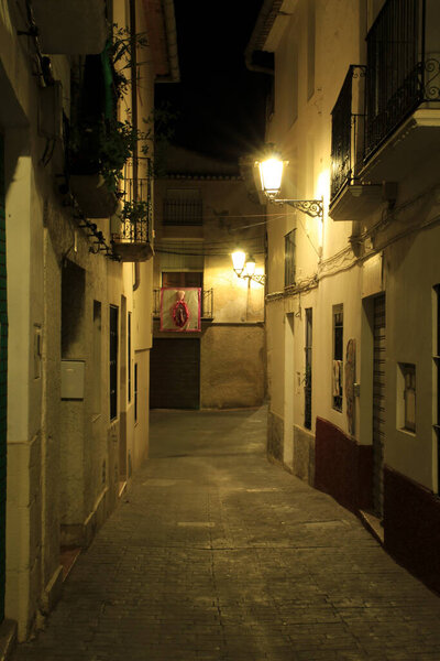 Narrow Street and typical facades at night of the Historical town of Benimantell in Alicante, Spain