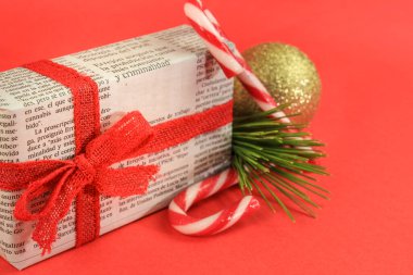 Madrid, İspanya - 17 Aralık 2021: Çam dalı, Noel tatlısı ve kırmızı arka planda altın toplarla sarılı eski bir gazeteye hediye