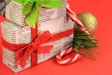 Madrid, İspanya - 17 Aralık 2021: Çam dalı, Noel tatlısı ve kırmızı arka planda altın toplarla eski gazetelere sarılı hediyeler