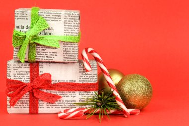 Madrid, İspanya - 17 Aralık 2021: Çam dalı, Noel tatlısı ve kırmızı arka planda altın toplarla eski gazetelere sarılı hediyeler