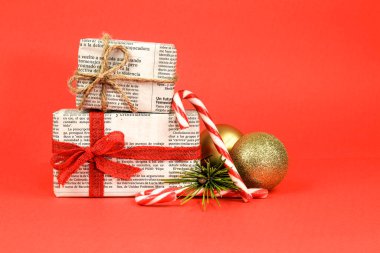 Madrid, İspanya - 17 Aralık 2021: Çam dalı, Noel tatlısı ve kırmızı arka planda altın toplarla eski gazetelere sarılı hediyeler