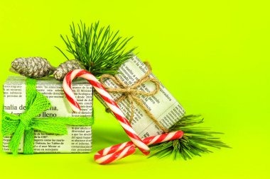 Alicante, İspanya - 17 Aralık 2021: Çam dalı, Noel tatlıları ve yeşil arka planda ip ile eski gazetelere sarılı hediyeler