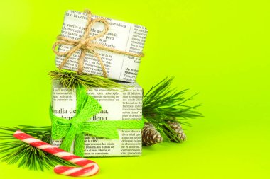 Alicante, İspanya - 17 Aralık 2021: Çam dalı, Noel tatlıları ve yeşil arka planda ip ile eski gazetelere sarılı hediyeler