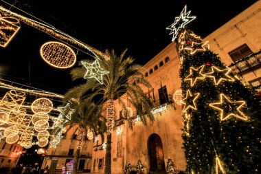 Elche, Alicante, İspanya... 20 Aralık 2021 'de insanlar Elche' nin aydınlatma ve Noel motifleriyle süslenmiş güzel sokaklarında eğlenip yürüyorlar.