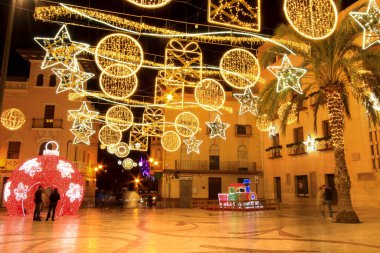 Elche, Alicante, İspanya... 20 Aralık 2021 'de insanlar Elche' nin aydınlatma ve Noel motifleriyle süslenmiş güzel sokaklarında eğlenip yürüyorlar.