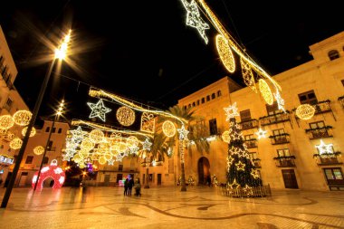 Elche, Alicante, İspanya... 20 Aralık 2021 'de insanlar Elche' nin aydınlatma ve Noel motifleriyle süslenmiş güzel sokaklarında eğlenip yürüyorlar.