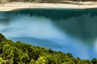 Güneşli bir günde çevresi bitki örtüsü ve dağlarla çevrili Guadalest köyünün renkli bataklığında yansımalar.