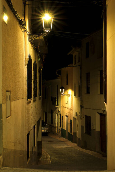 Benimantell, Alicante, Spain- November 26, 2021:Narrow Street and typical facades at night of the Historical town of Benimantell in Alicante, Spain