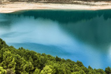 Güneşli bir günde çevresi bitki örtüsü ve dağlarla çevrili Guadalest köyünün renkli bataklığında yansımalar.