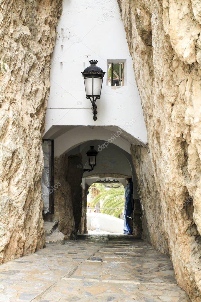 Narrow passage and typical whitewashed facade of the town of Guadalest in Alicante, Spain